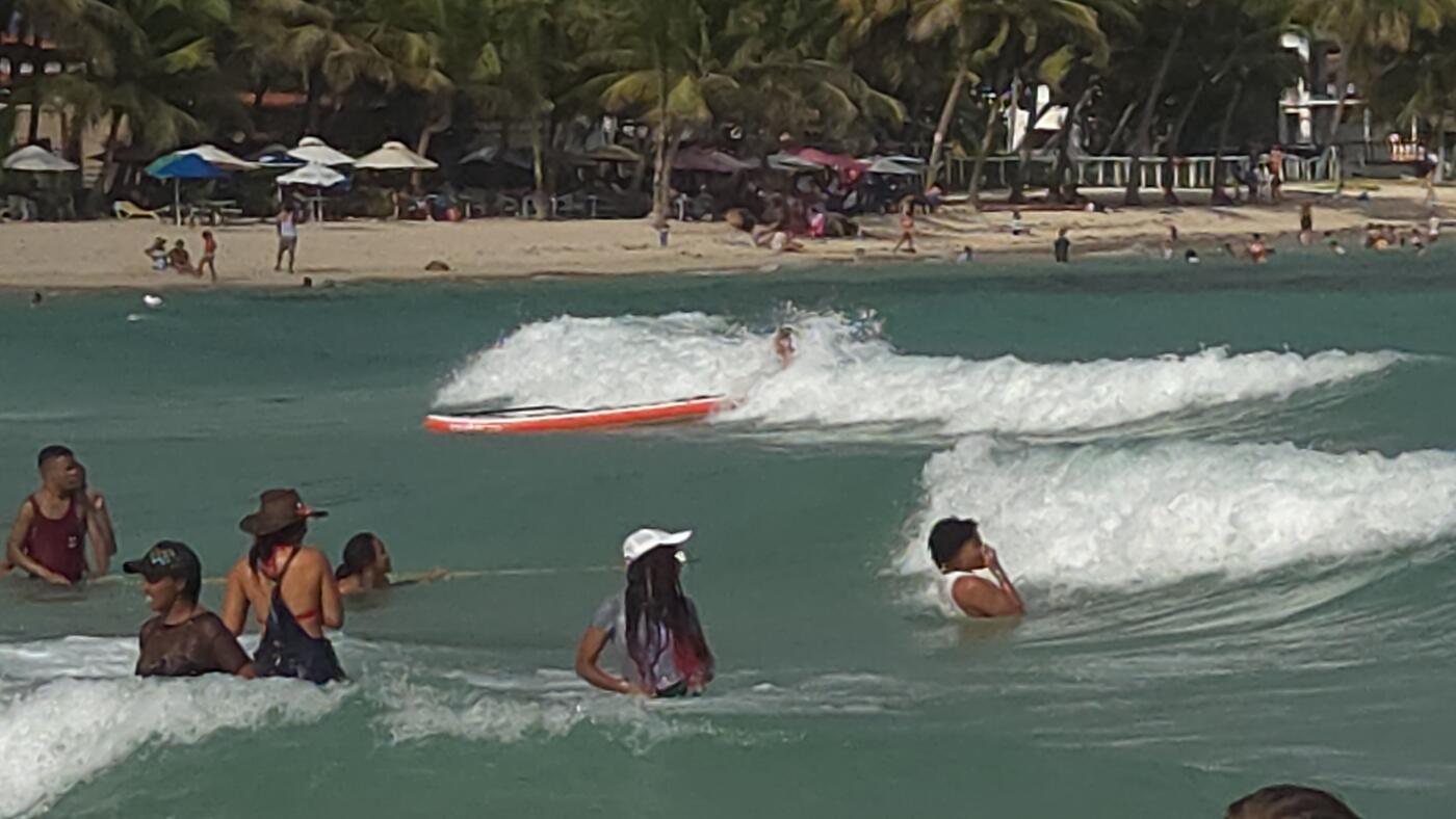 Santosh guests laugh in the turquoise shallows as a boat speeds past through the waves.